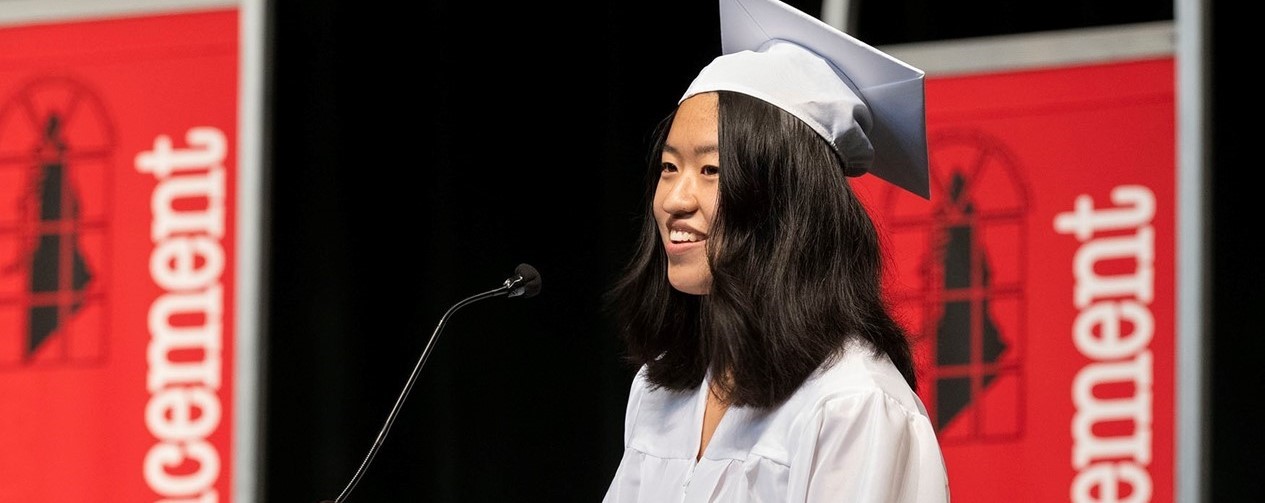 Student speaker at SHHS commencement wearing white cap and gown