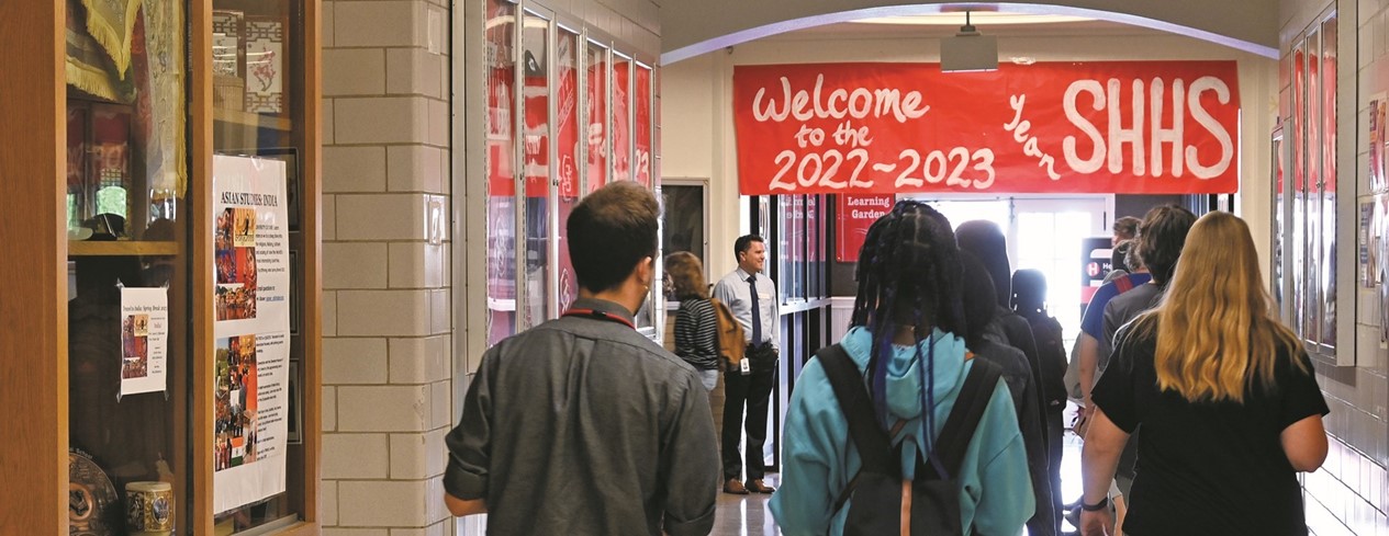 High School students walking under a red welcome banner