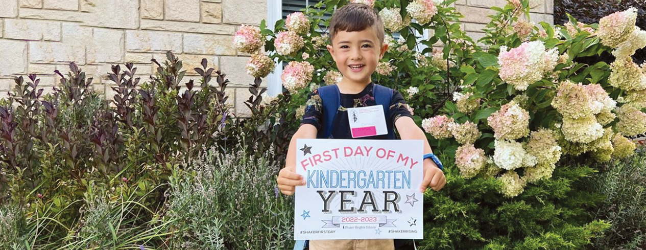 Male kindergarten student holding a first day of school sign